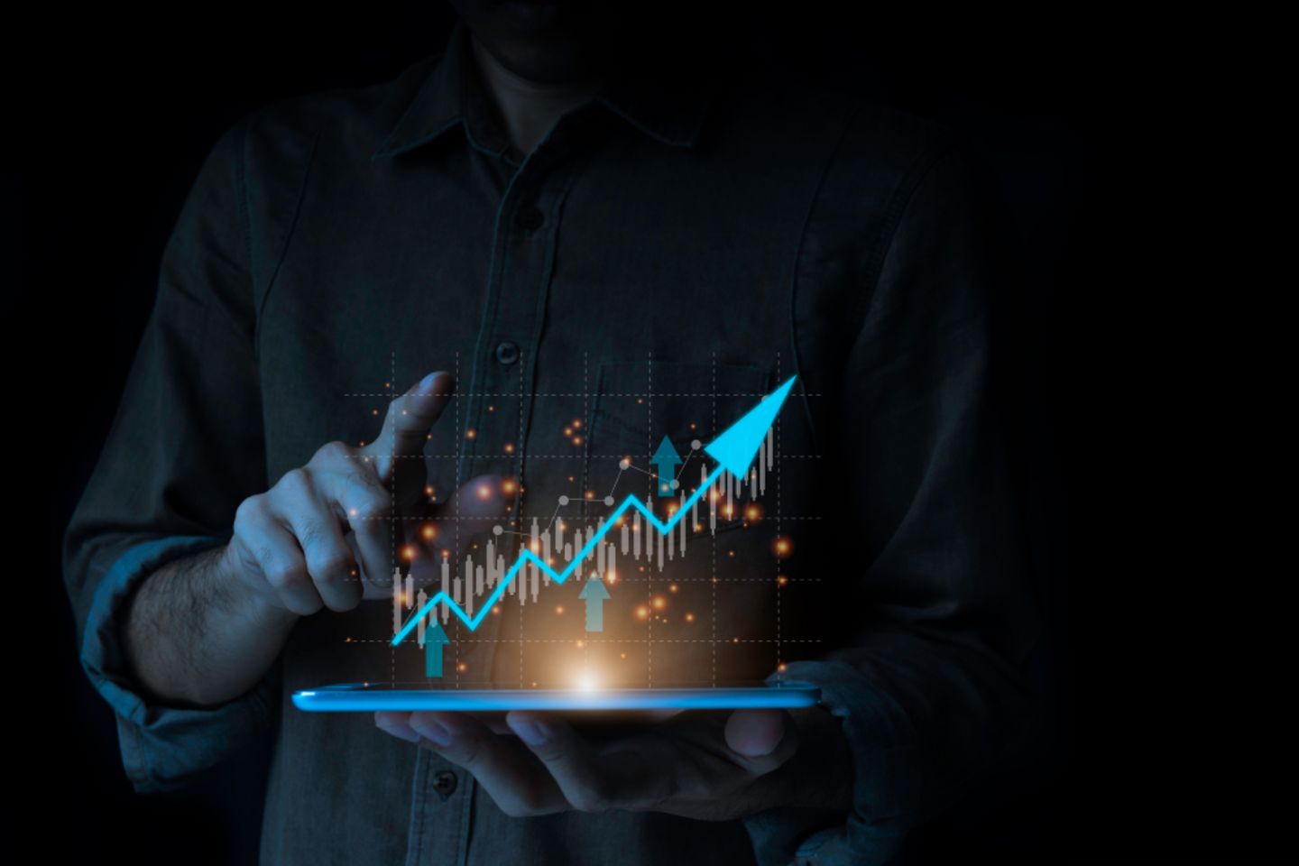 Person haelt Tablet und zeigt auf ein Diagramm mit einem aufwaerts verlaufendem Pfeil projeziert wird.