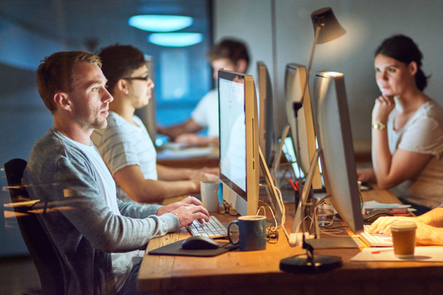 Five people sitting infront of monitors working.