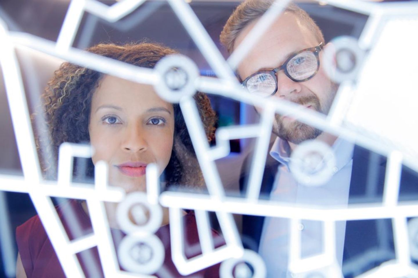 Um homem e uma mulher olham através de um visor futurista gerado de forma digital.