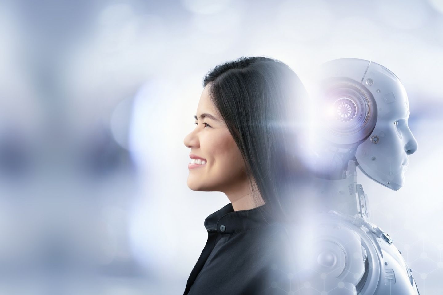 A smiling woman is leaning back to back with a robot.