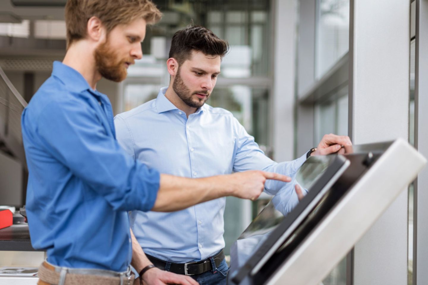 Zwei Geschäftsmänner benutzen einen Touchscreen