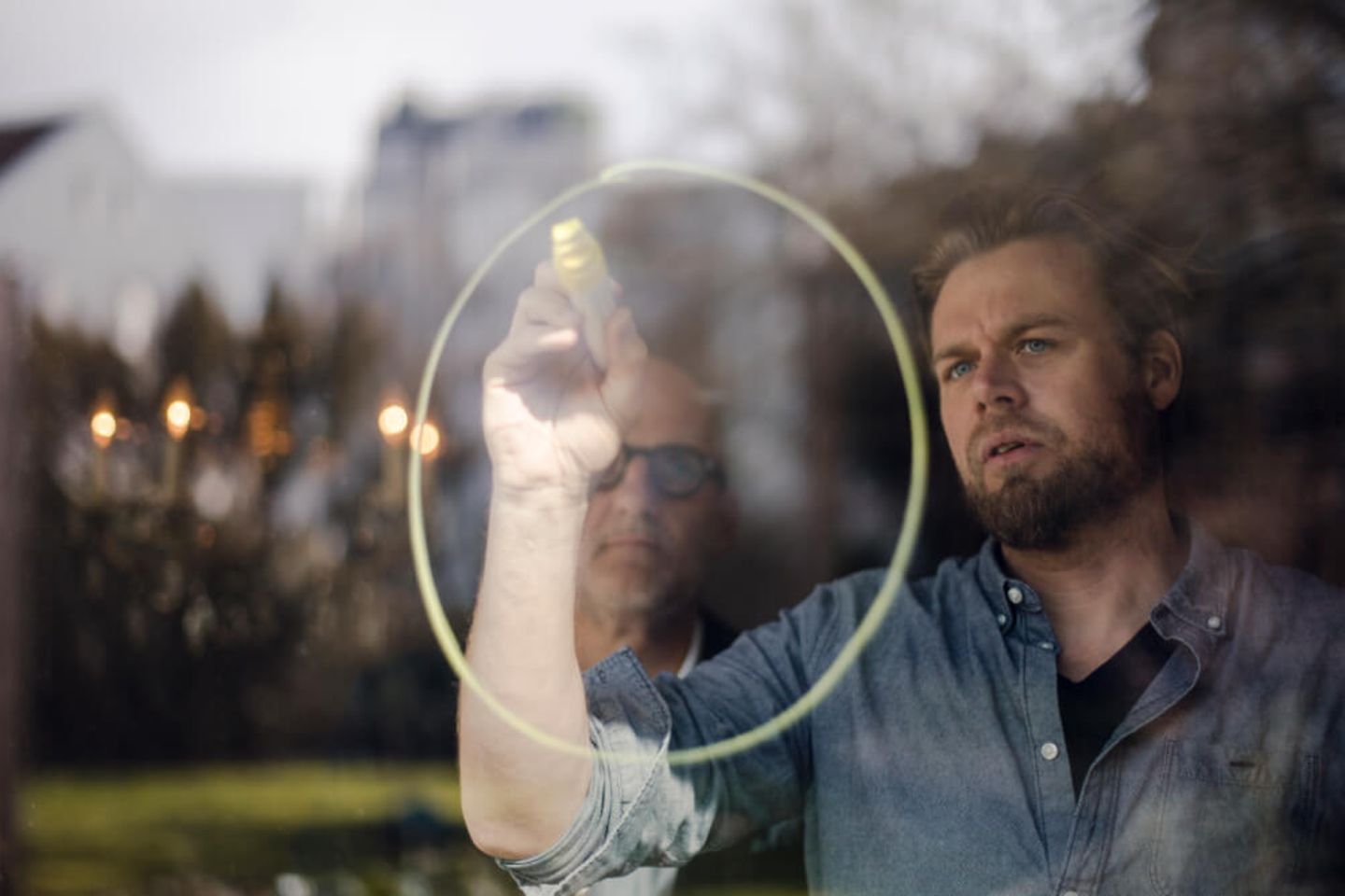 A man paints a big yellow circle on a window