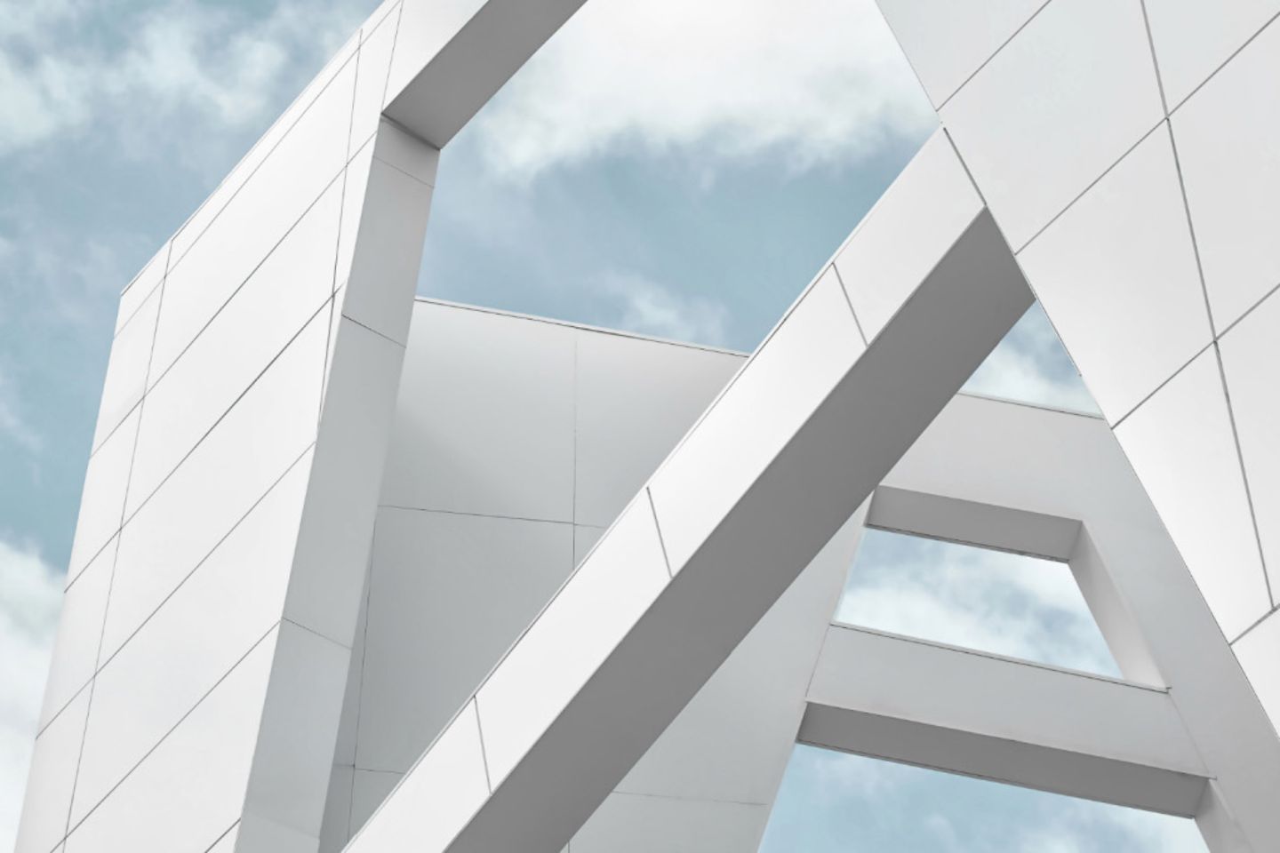 Large white walls of a building against a blue sky with white clouds.