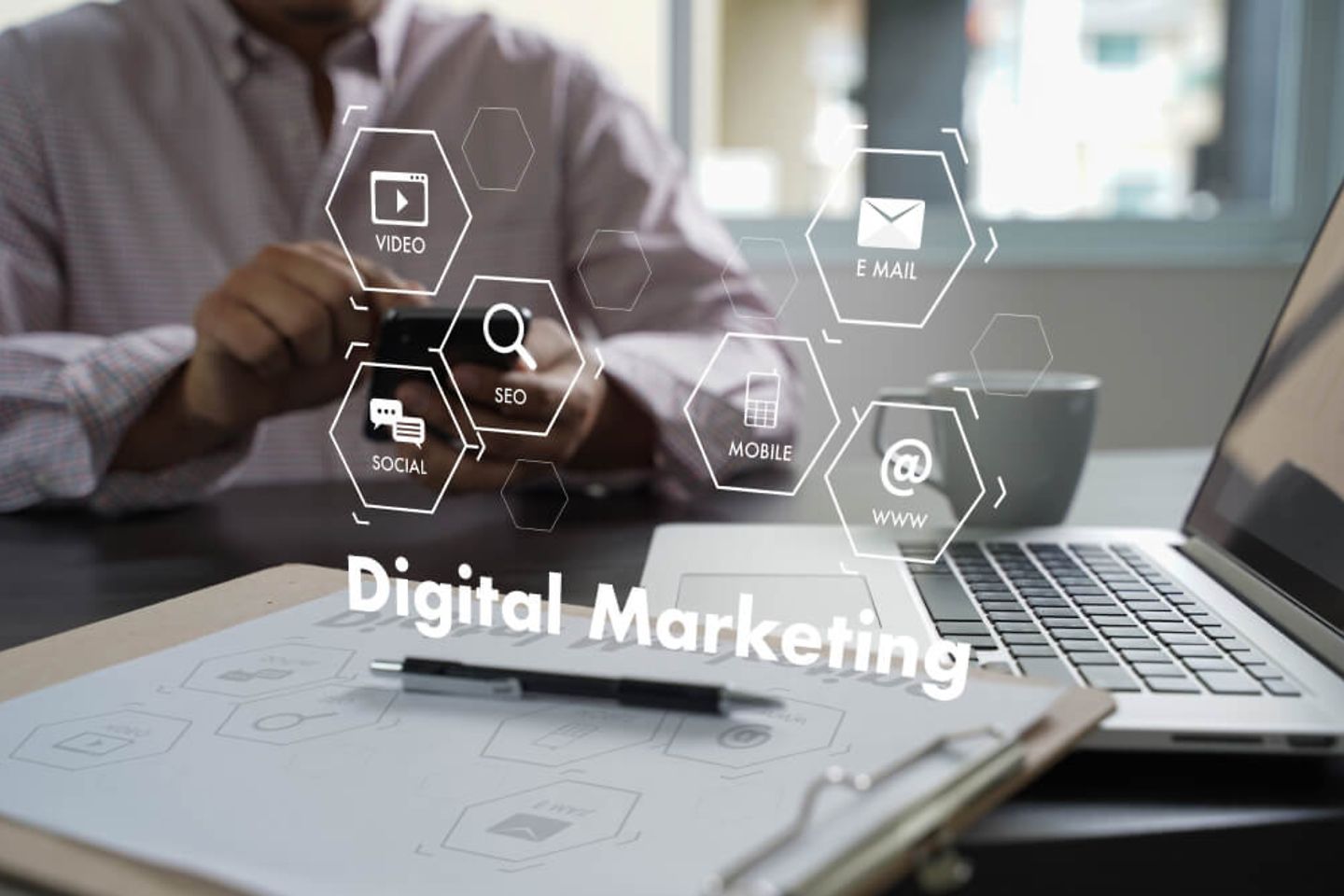 "Digital Marketing" in großer weißer Schrift mit unterschiedlichen Icons drumherum. Im Hintergrund: klassisches Büro Setting 
