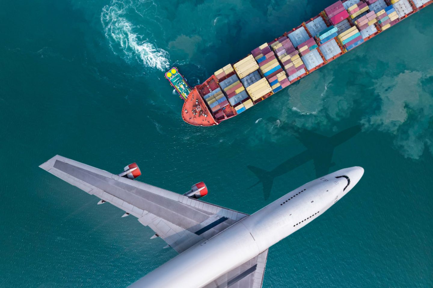 From a bird's eye view, an airplane and a ship cross the ocean.