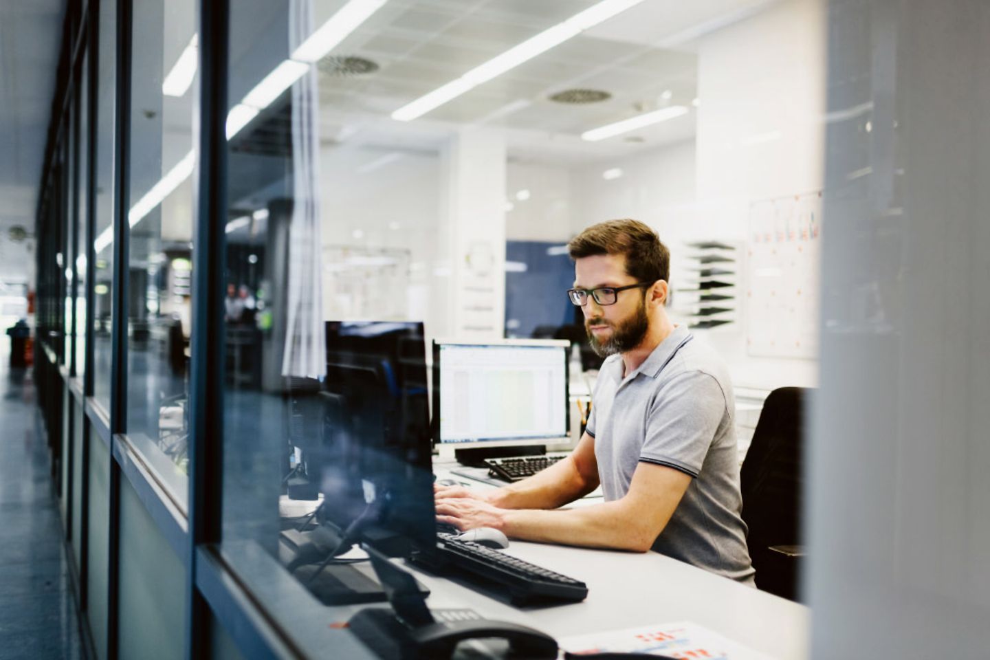 Ein Mann sitzt vor seinem Schreibtisch und schaut auf einen Computerbildschirm 