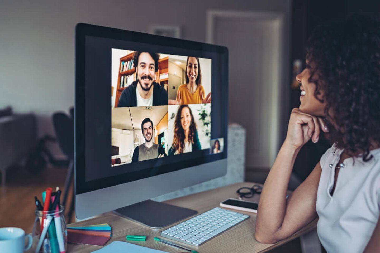 Woman smiling at her screen with four other people on it 