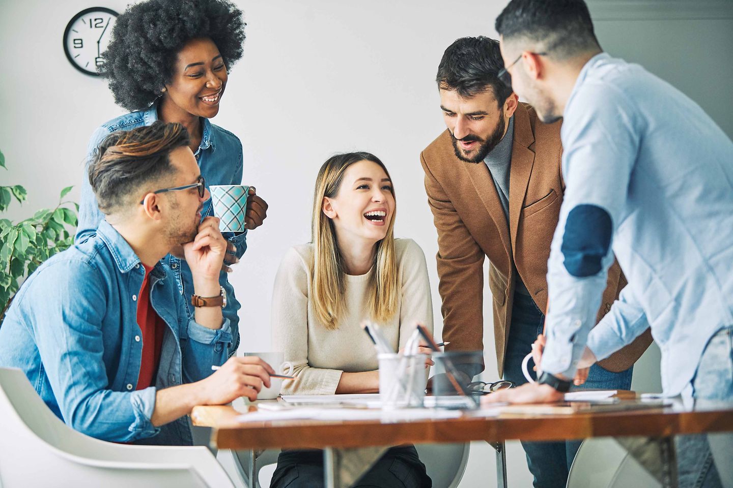 Fünf Young Professionals im Digital Marketing arbeiten glücklich zusammen