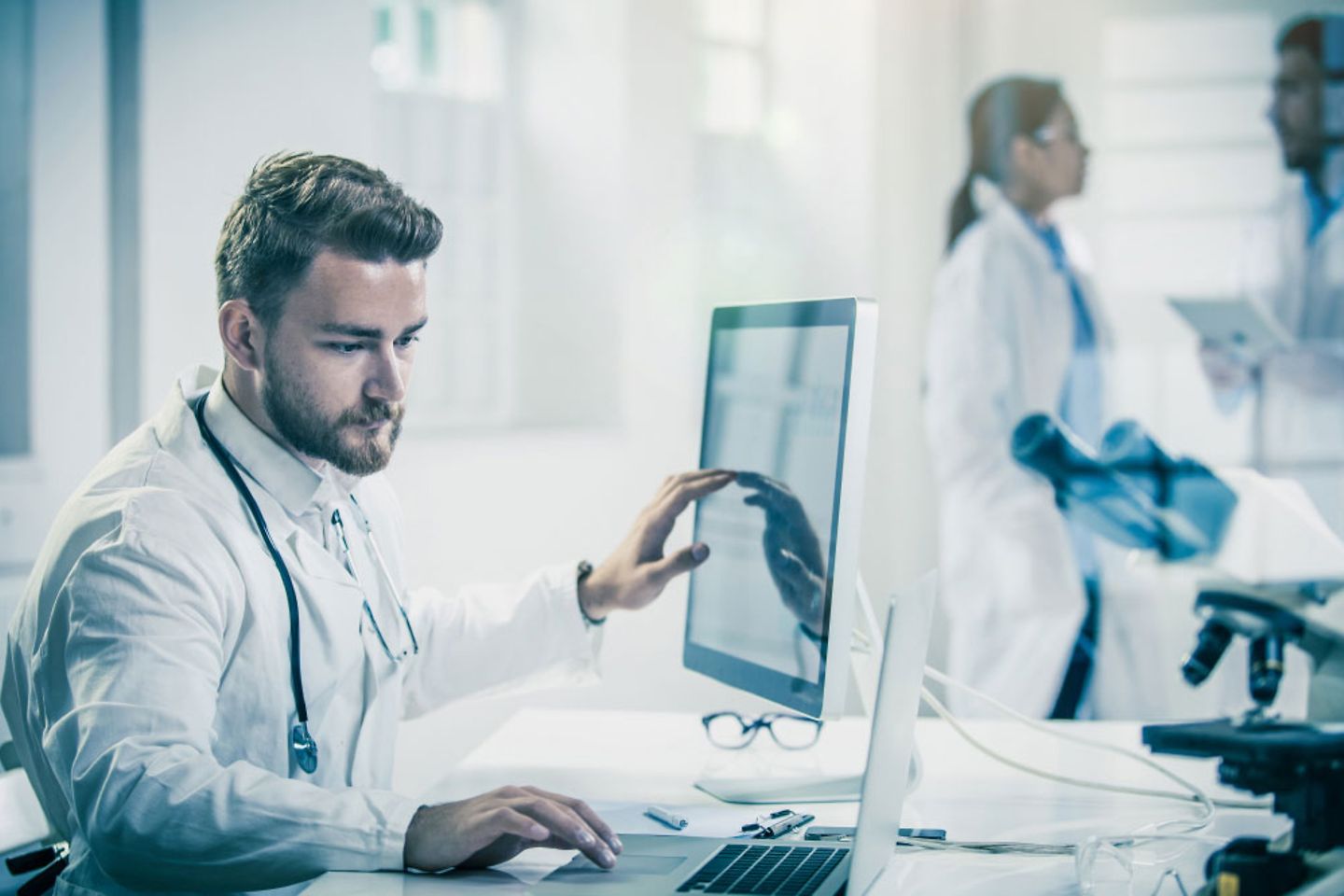 Doctor in front of a computer with colleagues behind them