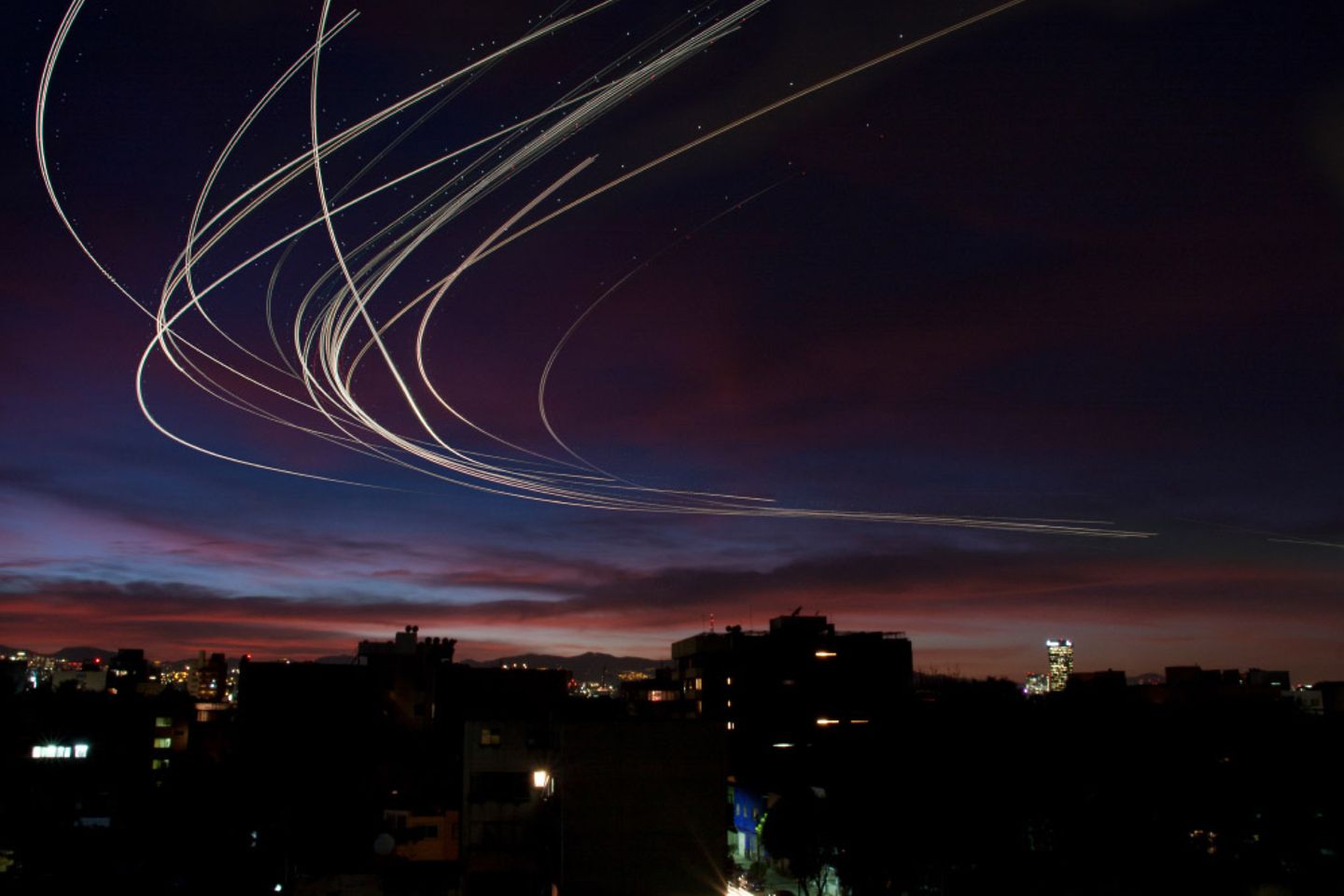 Vliegtuigsporen in donkerblauwe en violetgekleurde lucht.