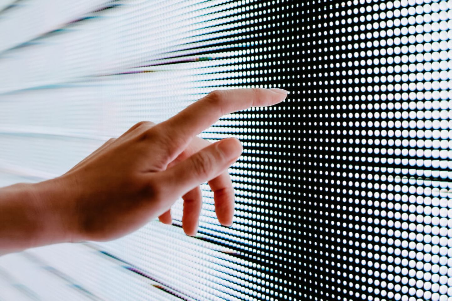 Hand touches digital screen with dots