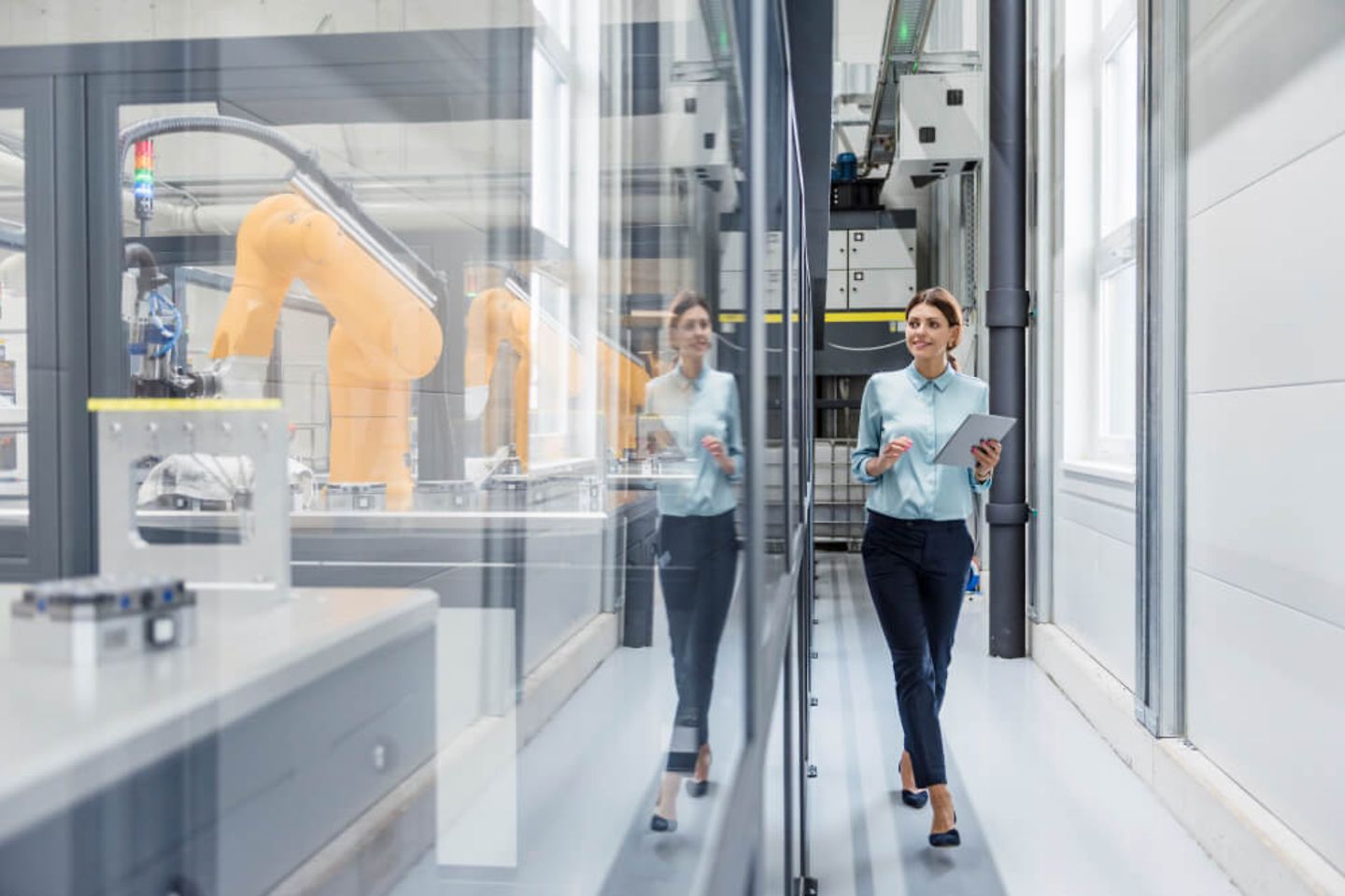 Woman walking through a factory building holding a notebook