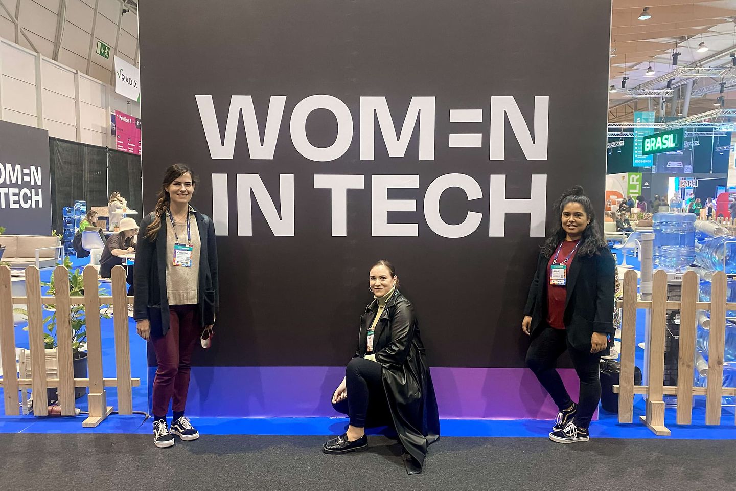 Drei Frauen vor einer Wand mit der Unterschrift von Frauen in der Technologiebranche
