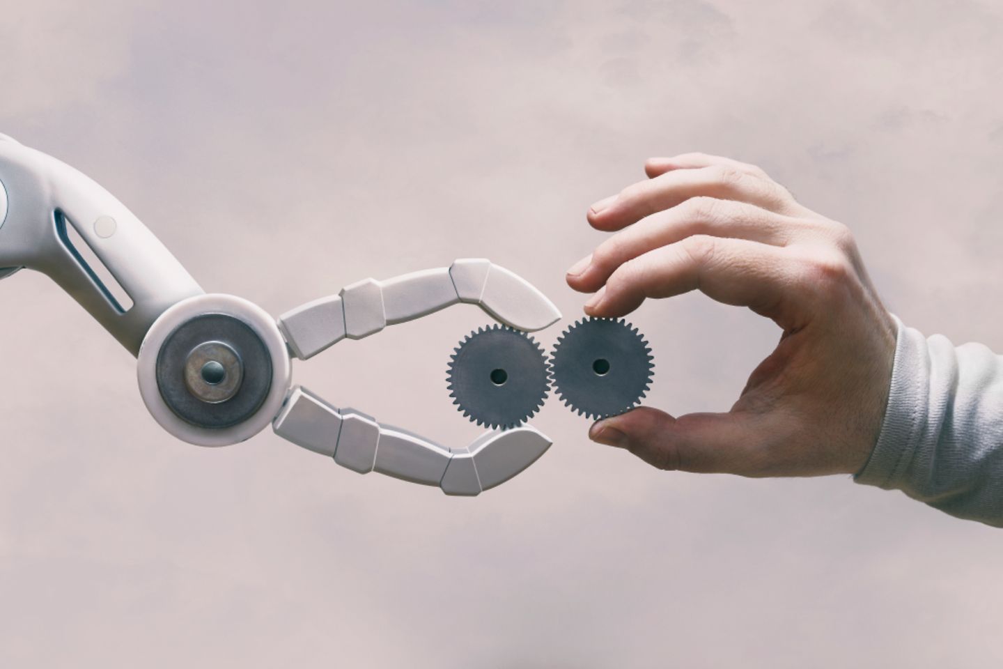 A hand and a robot are holding gears and meet in the middle of the picture 