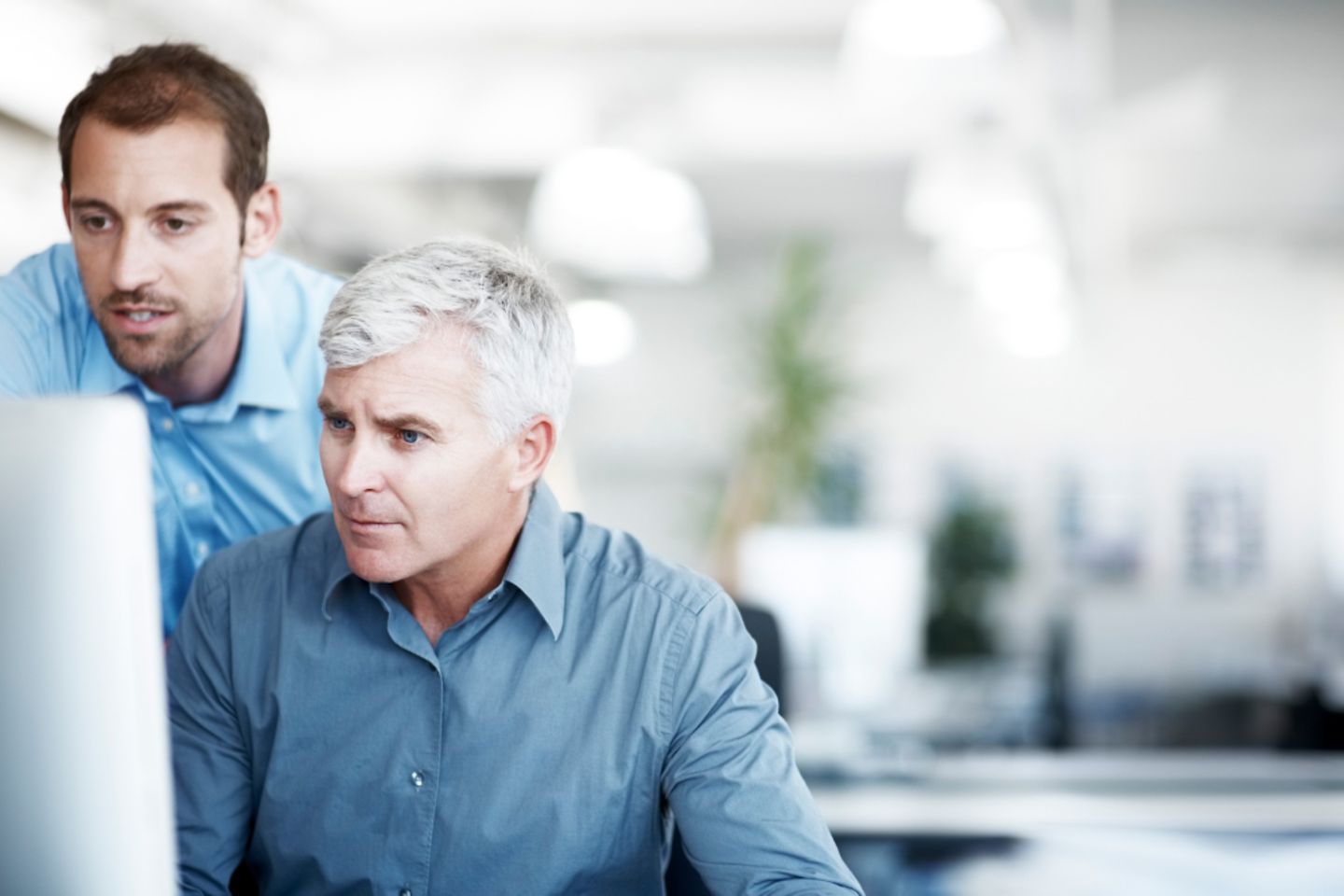 Two men looking at a screen infront of a blury background 