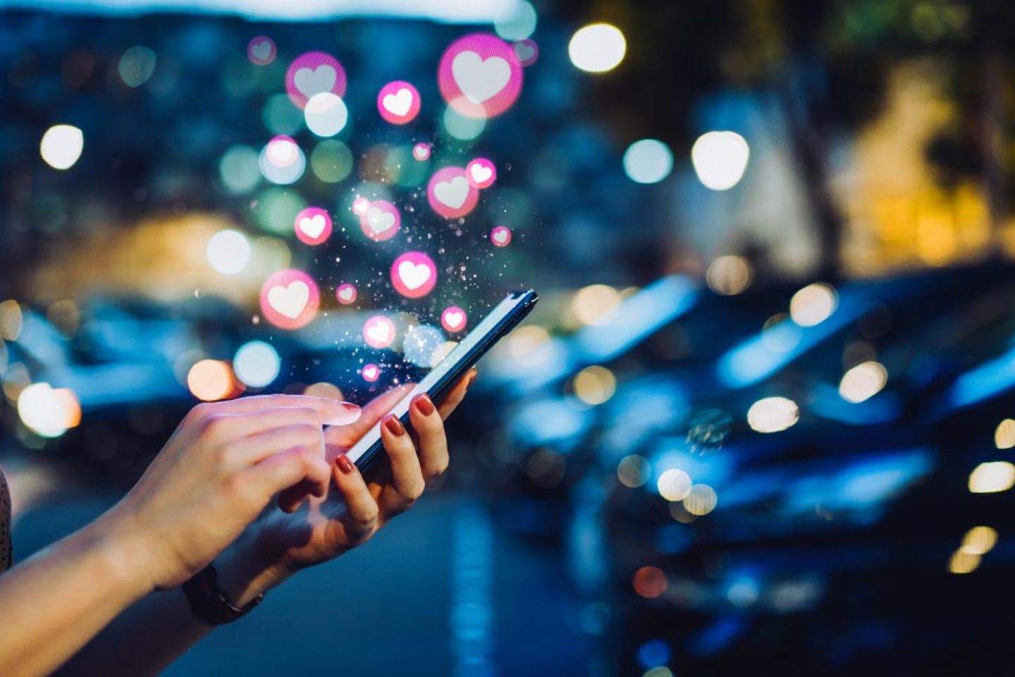 Woman holding smartphone with heart symbols coming out of it