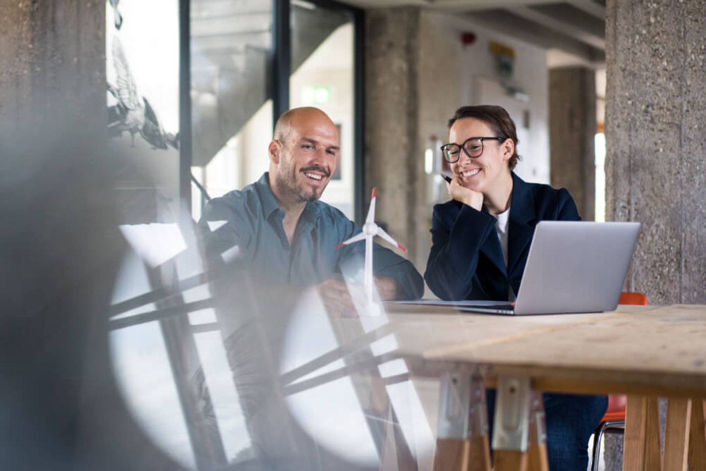 Business people with laptop looking at wind turbine toy