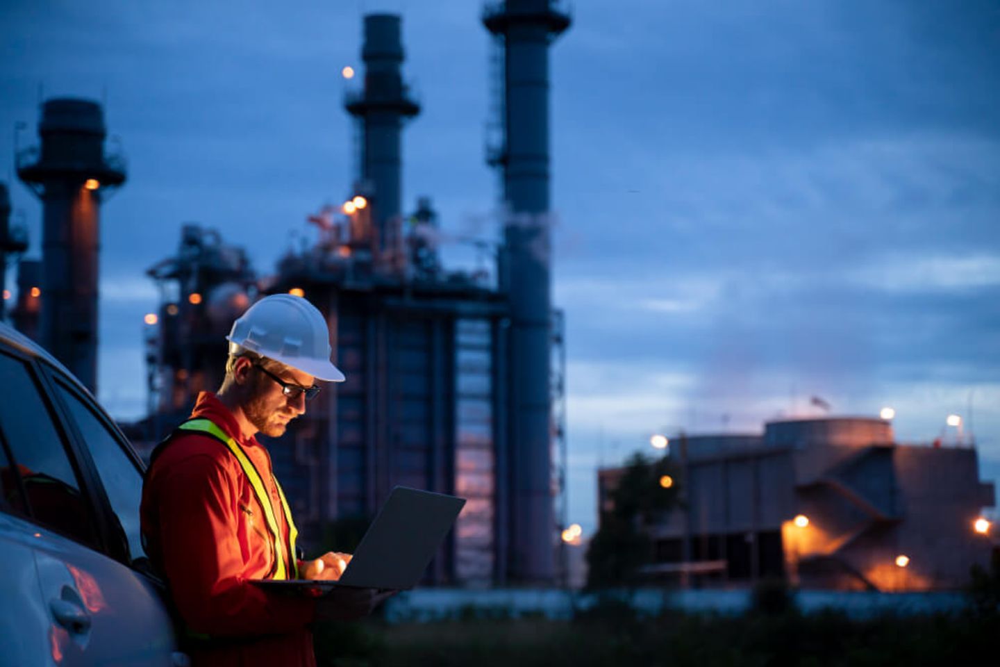 Mann steht neben einer Industrie mit einem Laptop in der Hand