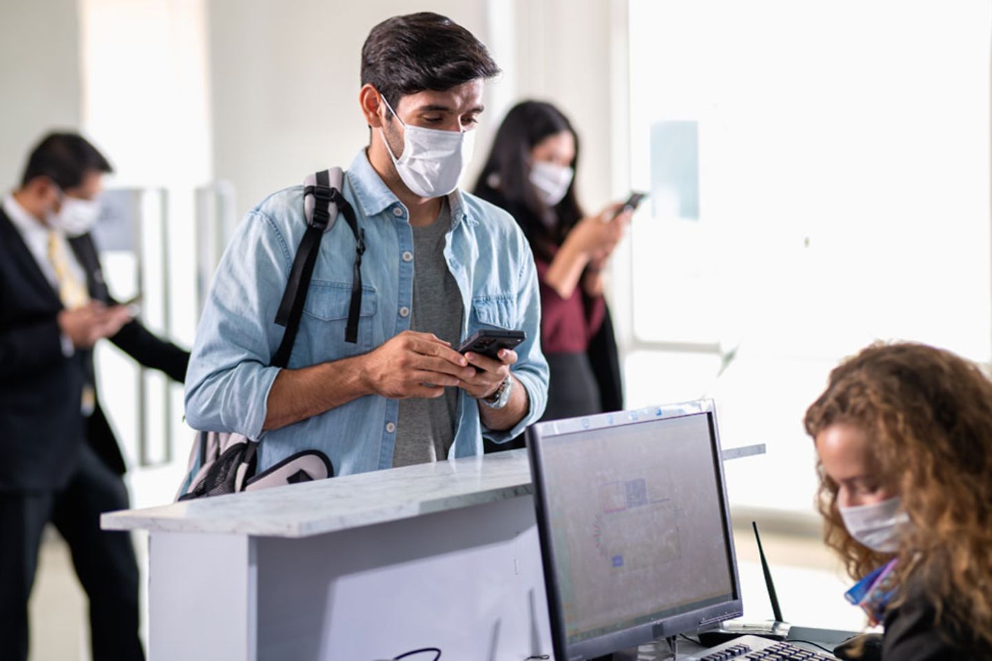  Groep vliegtuigtoeristen dragen een mondmasker en wachten op de bagage en boarding pass op vliegveld toegangsbalie / check in.