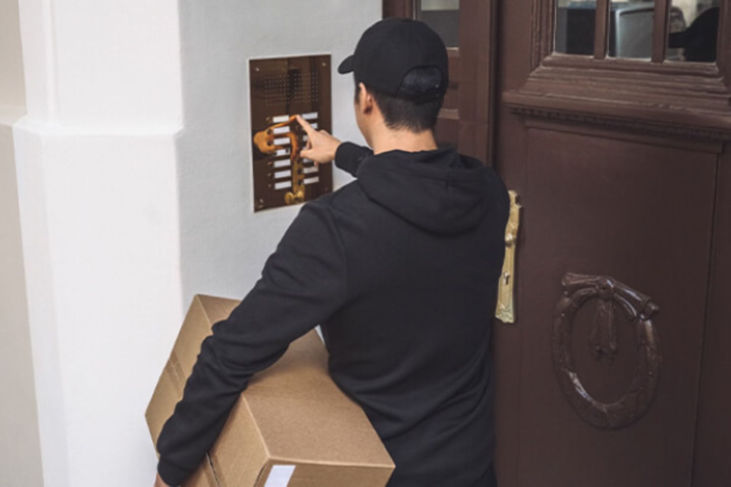 Courier man is ringing the bell at a house entrance holding a package