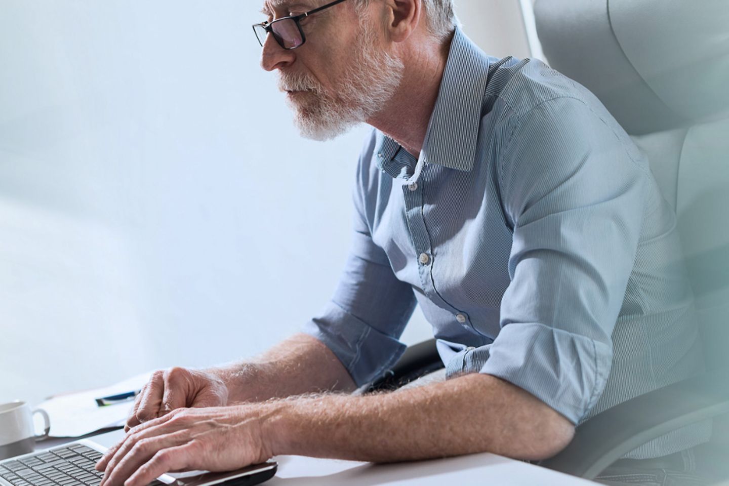 Geschäftsmann sitzt am Schreibtisch und arbeitet auf Laptop