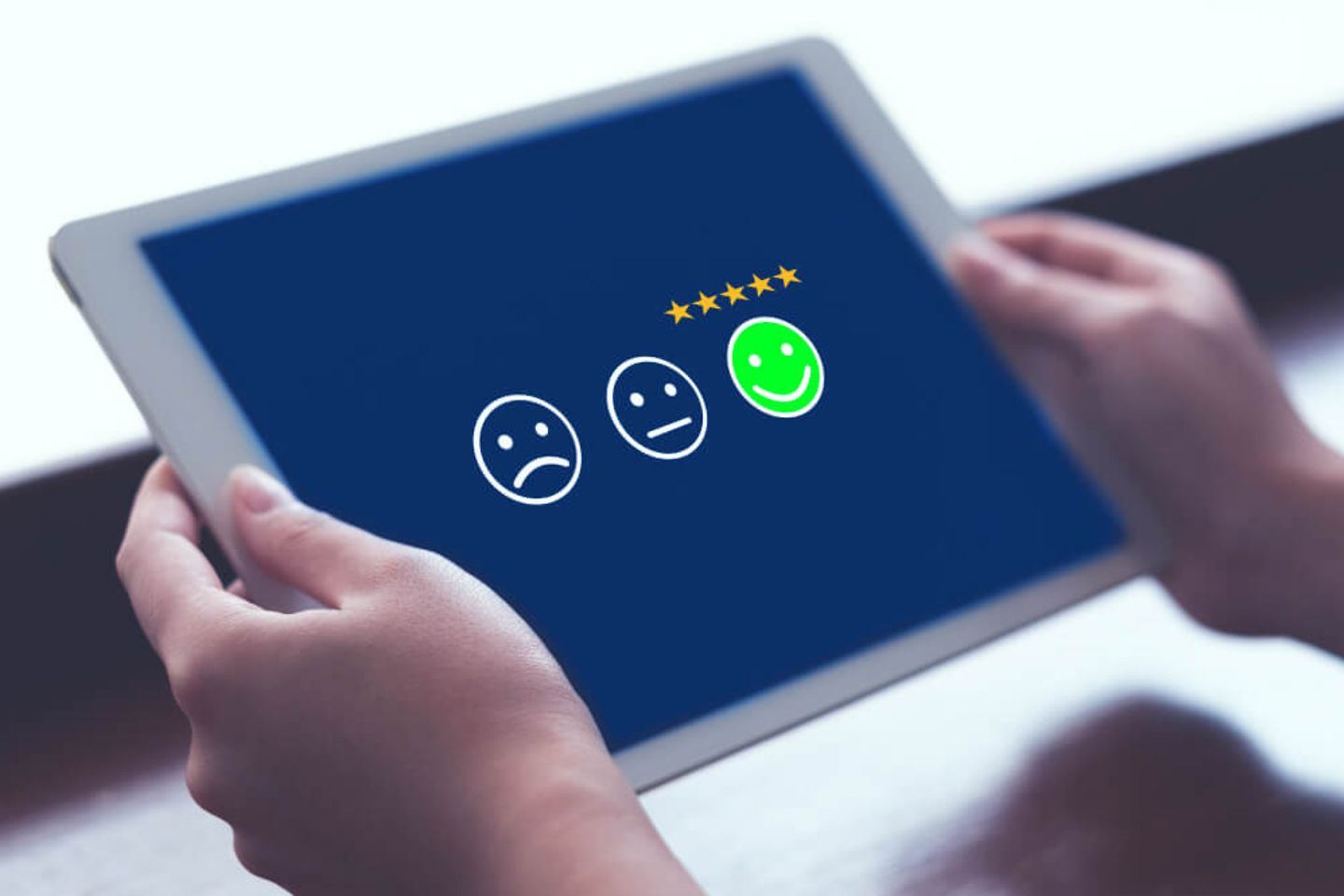 Person holding a tablet with a customer review showing s smiley face in green