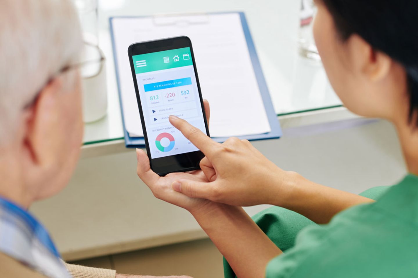 nurse showing senior patient how to keep food diary via mobile application