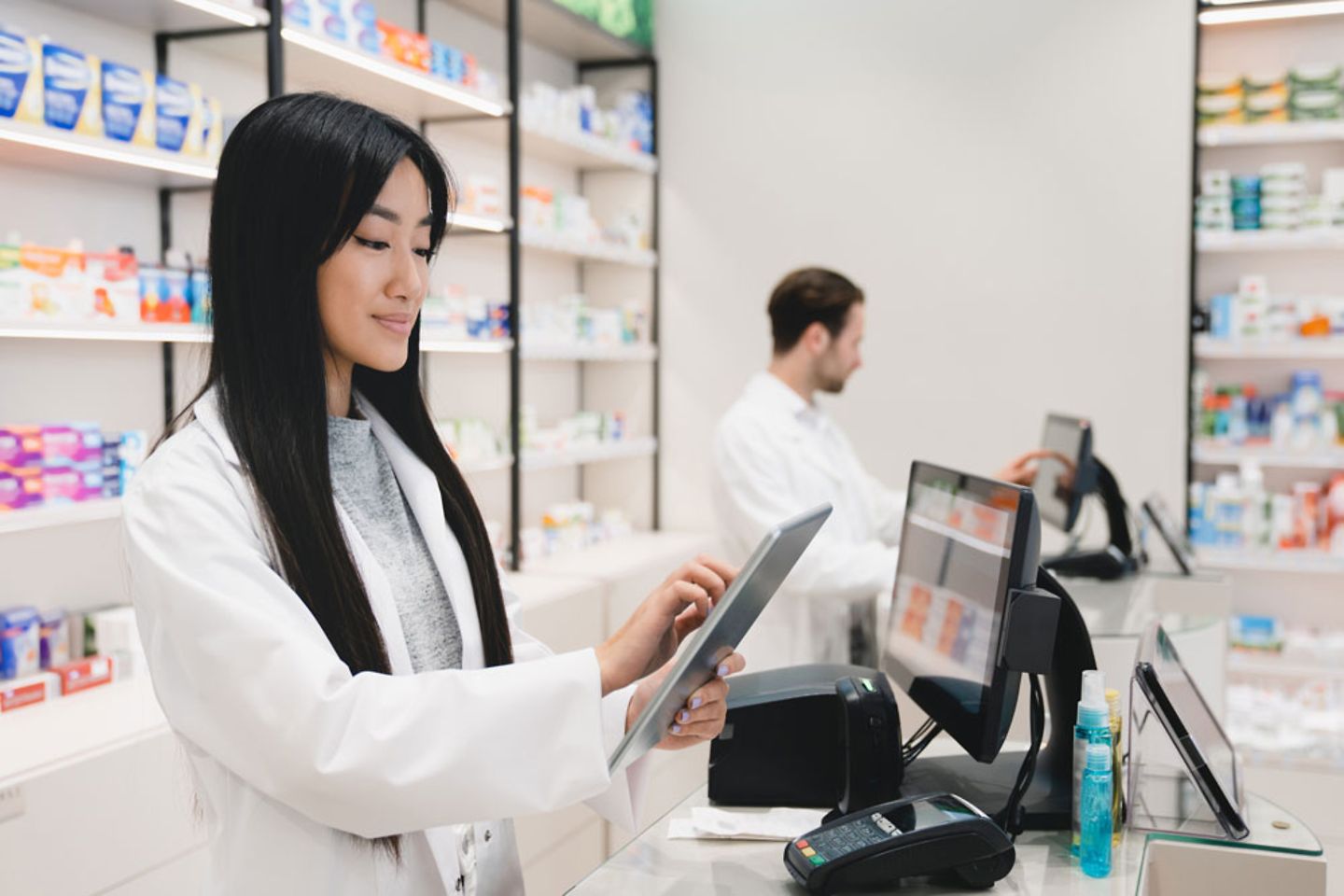 pharmacists selling medications standing at cash point desk in pharmacy drugstore