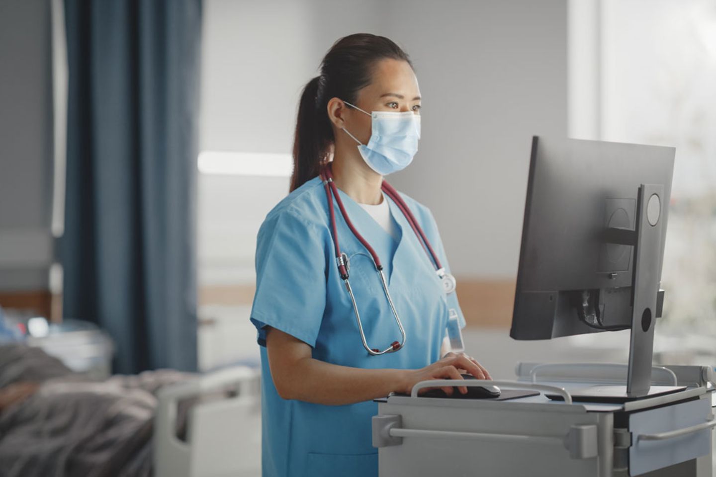 doctor wearing face mask uses medical computer, checking patient's medical data