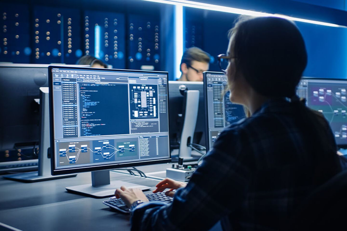 IT engineers work in the System Control Center filled with monitors and servers