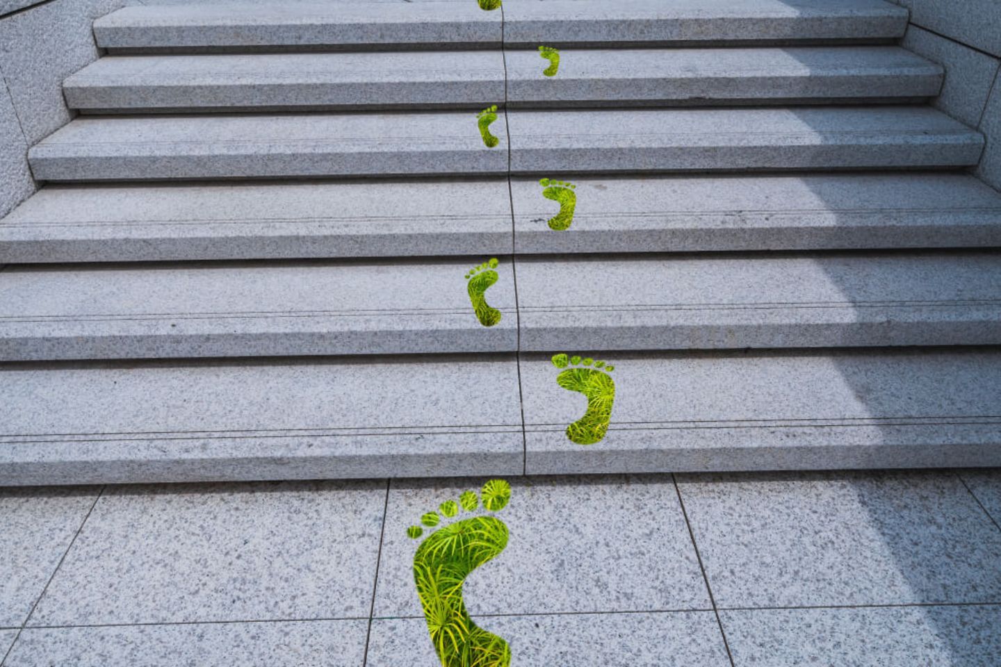 Grüne Fußabdrücke auf den Stufen symbolisieren den Kohlenstoff-Fußabdruck.