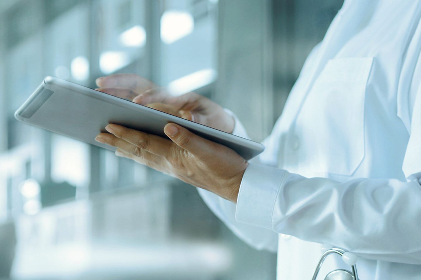 Doctor in hallway reviewing electronic health records on digital tablet