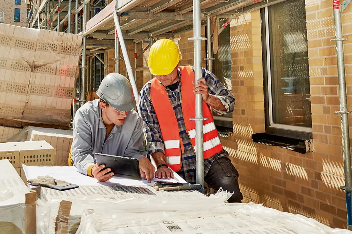 Zwei Personen schauen auf einer Baustelle in Planungsunterlagen