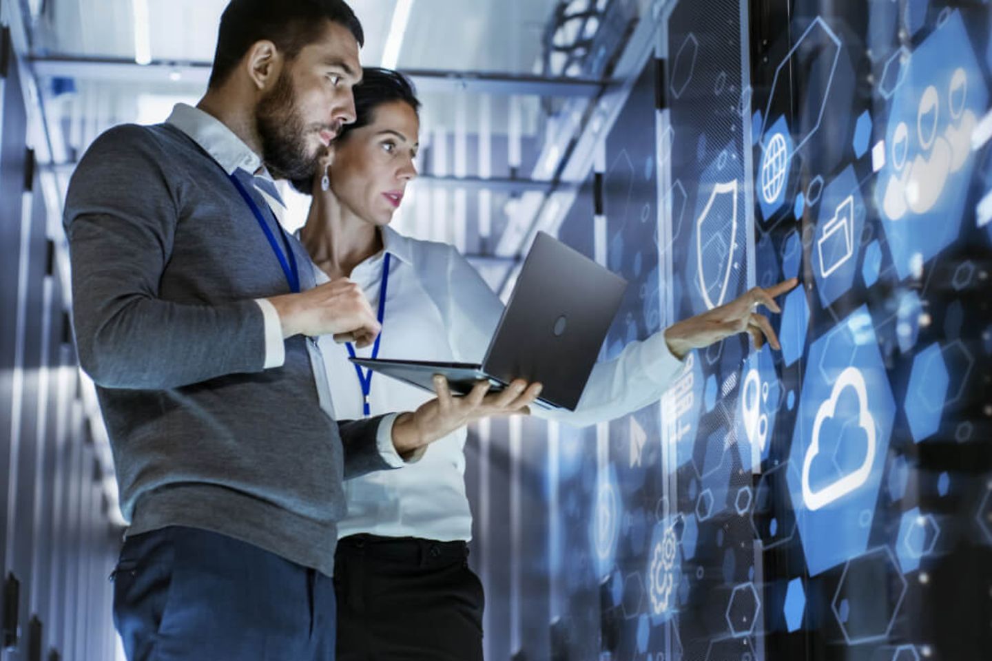 IT specialist holds laptop and discusses work with server technician