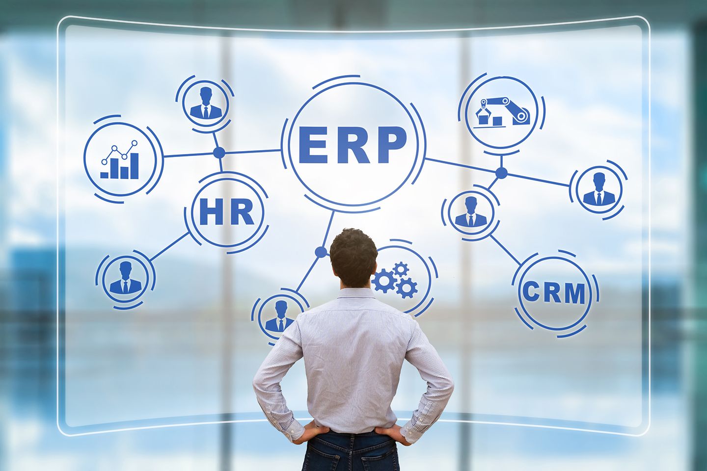 Mann schaut auf digitale Wand, auf der Mindmap zu sehen ist mit Begriffen wie ERP, HR, CRM.