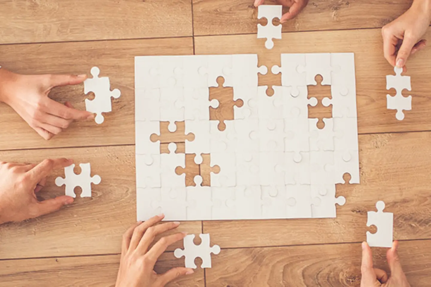 Viele Hände, die zusammen ein Puzzle spielen