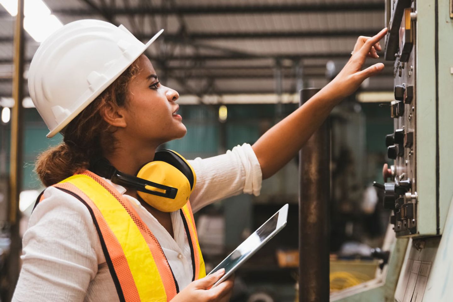 Industrial factory maintenance engineers woman inspects a relay protection system of machinery holding digital tablet.