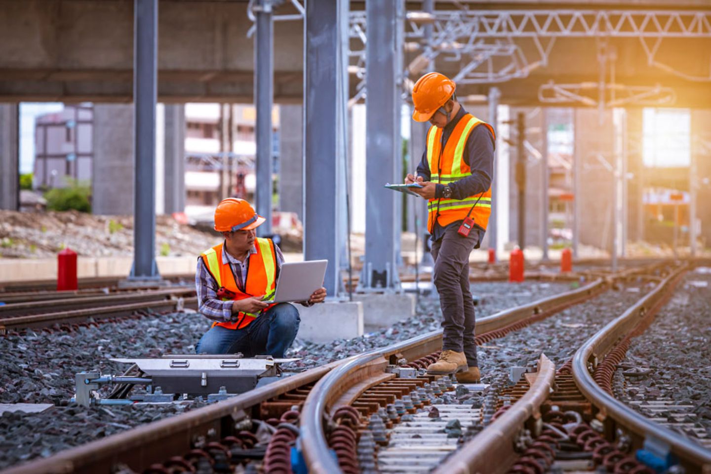 Two engineers checking railway switch on railroad station, wearing a safety uniform and helmet. 