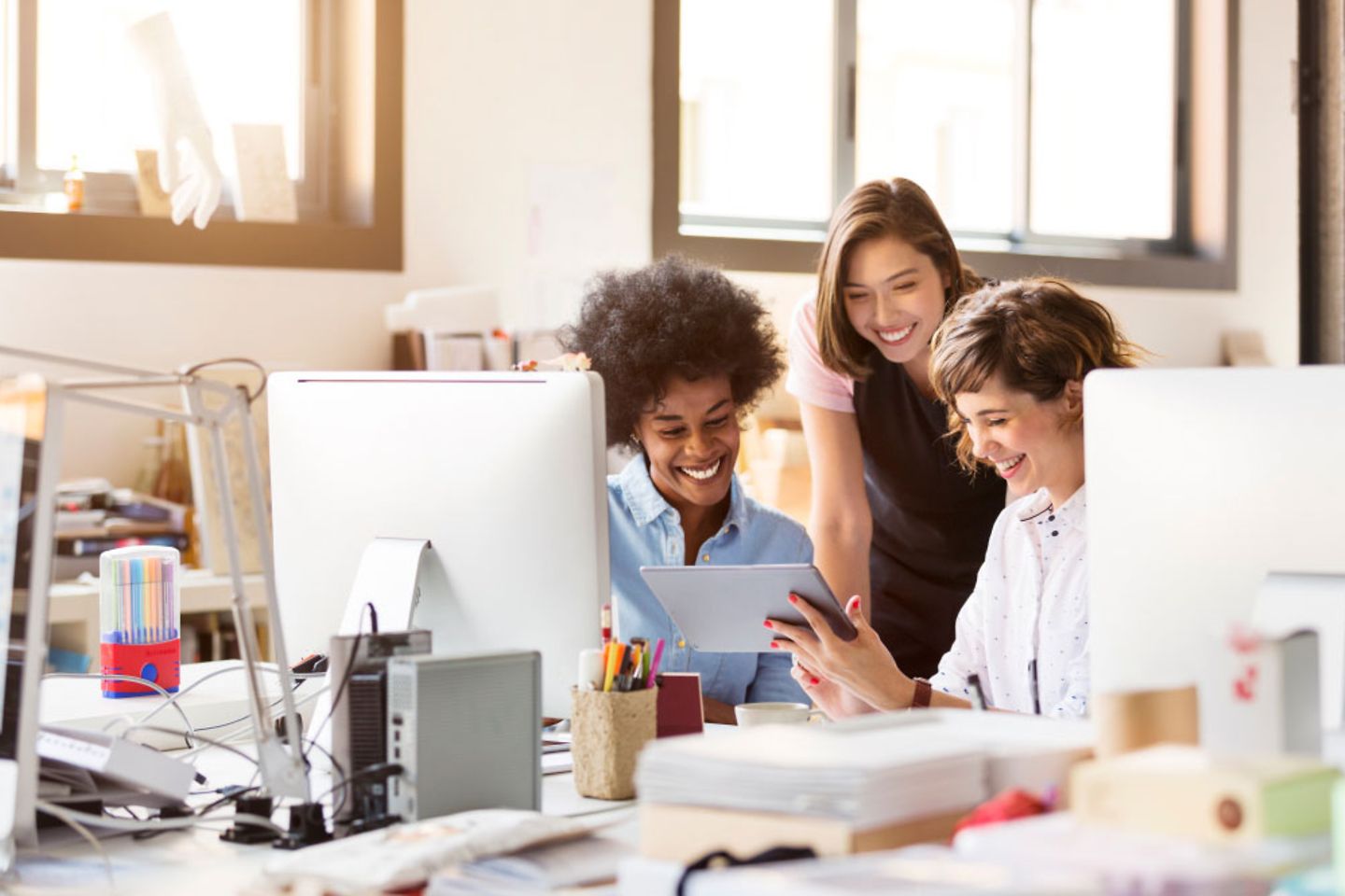 A group of women discussing something on a tablet in the office