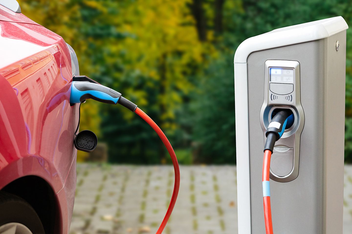 Close-up of an electric car with a cable connected and a charging station 