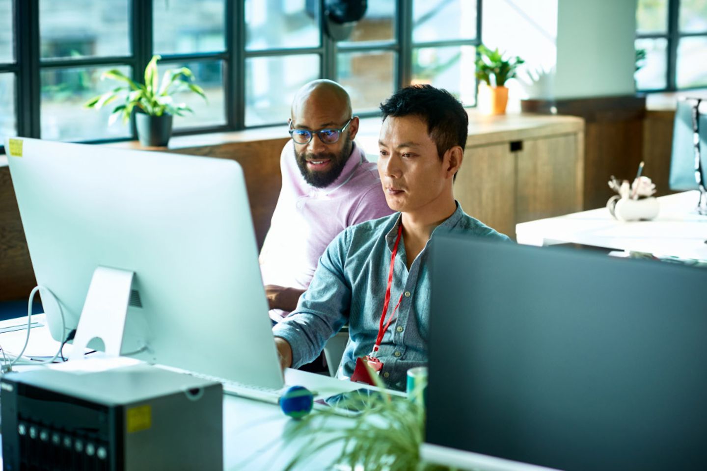 A man showing his colleague something on the computer