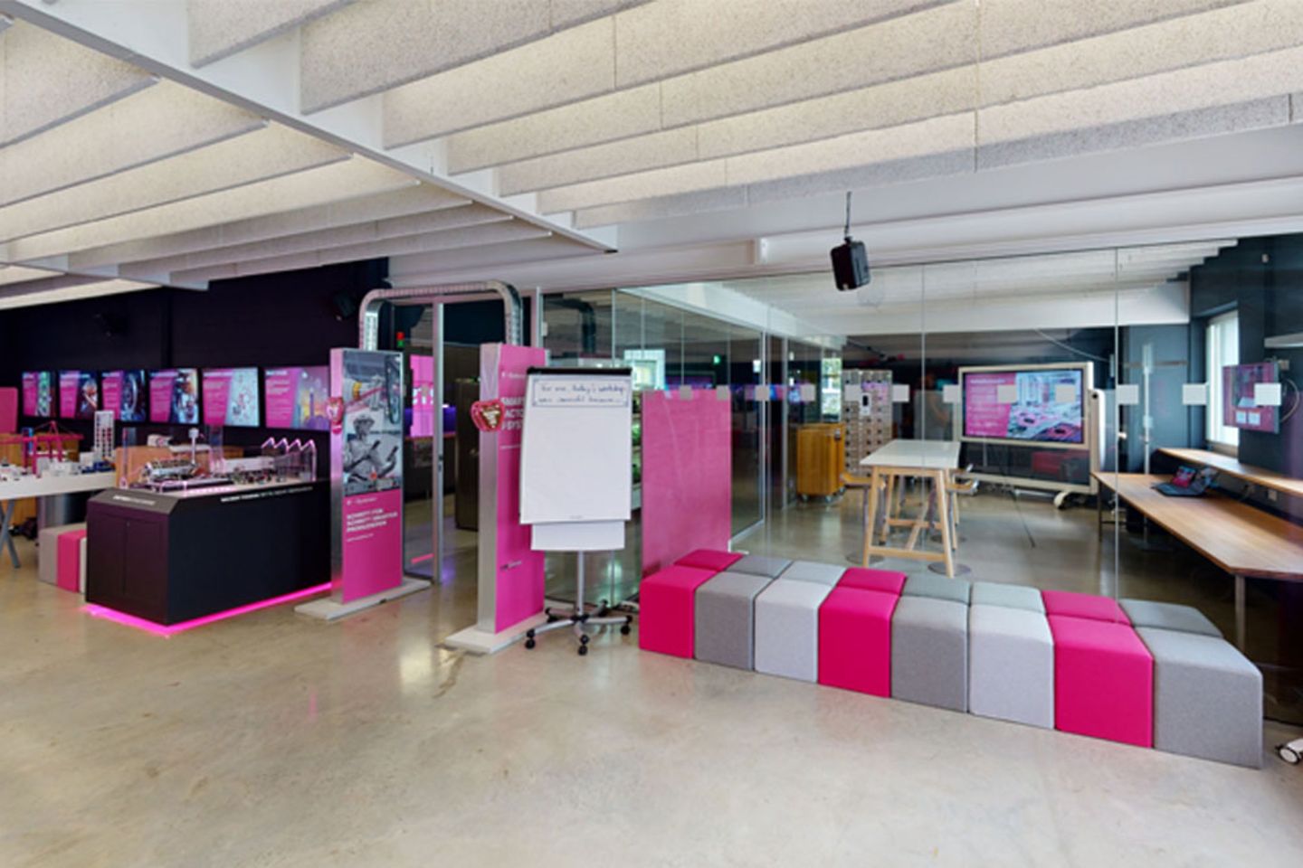 Salle d’atelier du centre d’innovation remplie de sièges colorés, séparée par une paroi de verre