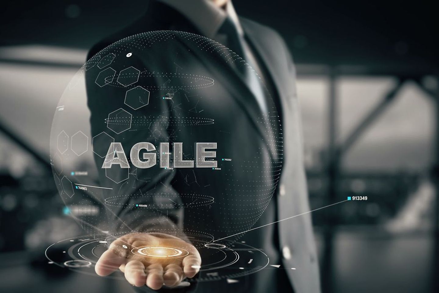 A man in a suit holds the word Agile in one hand