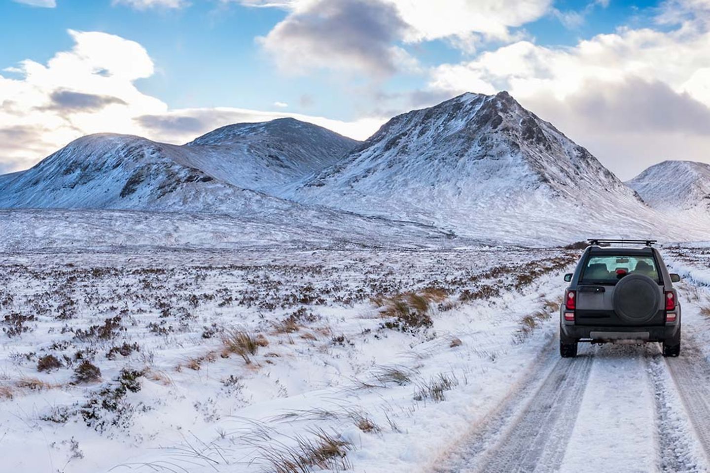 An off road vehicle in a snowy landscape with mountains