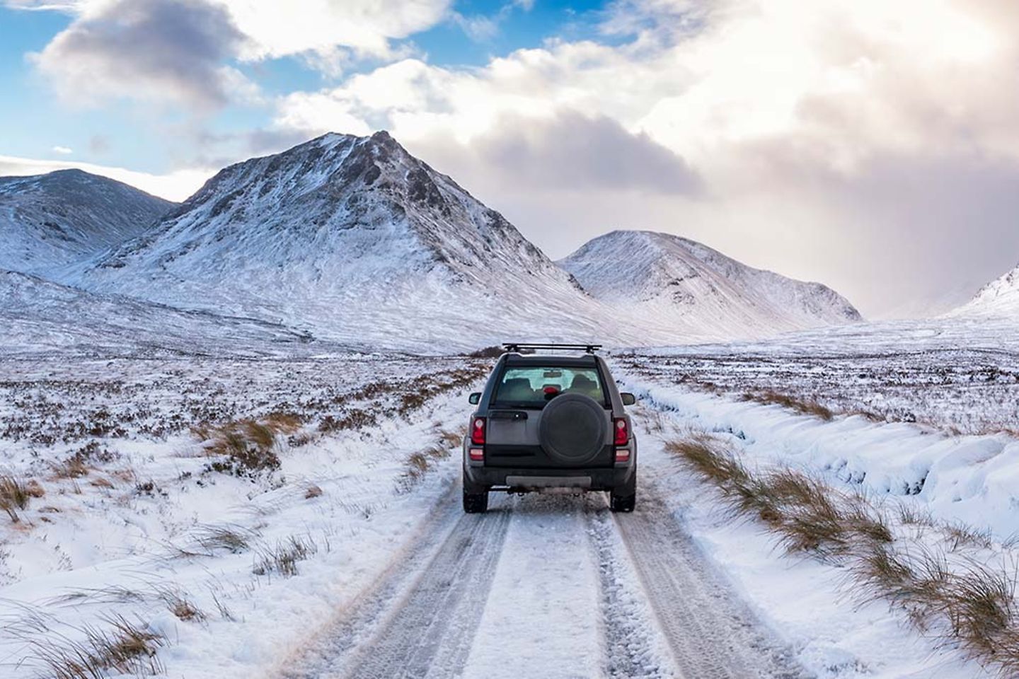 Een terreinwagen in een sneeuwlandschap met bergen