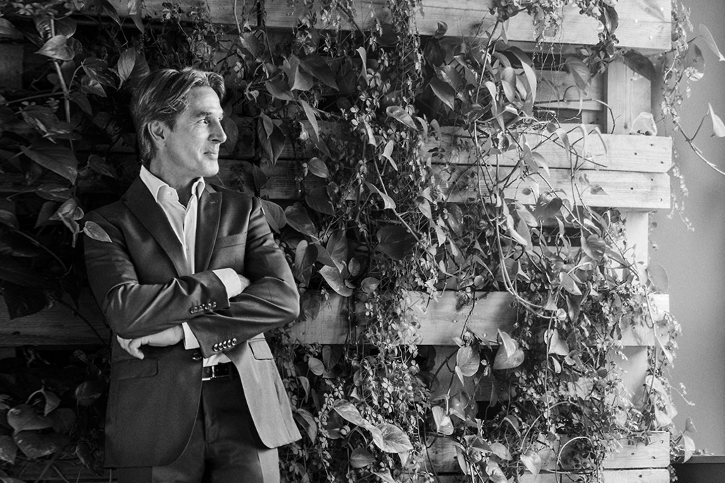 black and white picture of man in suit standing in front of overgrown wall