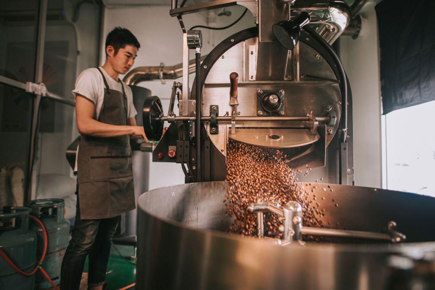 Ein Mann röstet Kaffee an einer großen Maschine