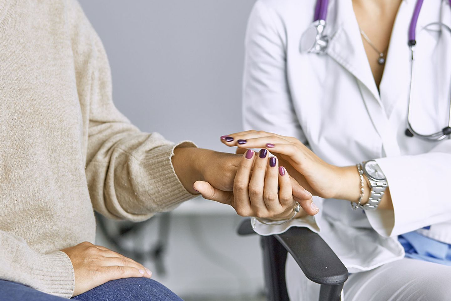 A doctor holds a patient's hand