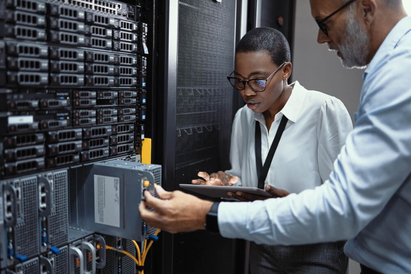 Two IT professionals working in a server room