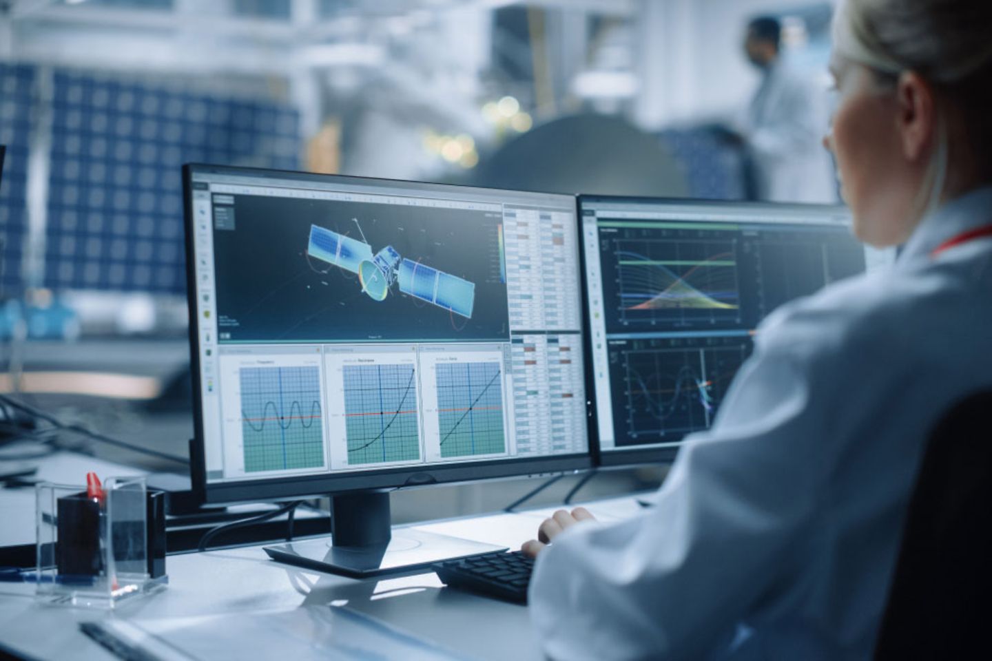 Een ingenieur analyseert een satelliet op een computer